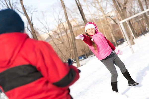 Děti v zimě parku hrají sněhové koule — Stock fotografie