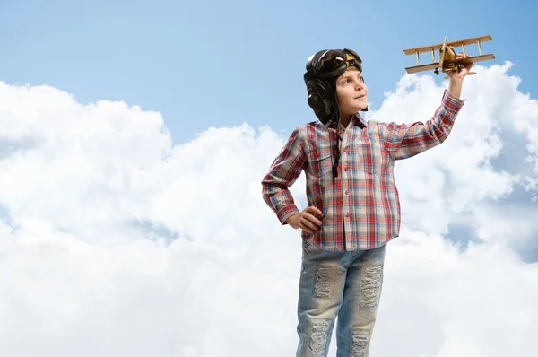 Menino no piloto de capacete brincando com um avião de brinquedo — Fotografia de Stock