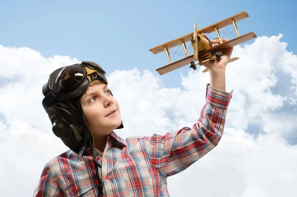 Garçon dans casque pilote jouer avec un jouet avion — Photo