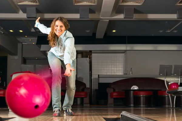 Příjemná mladá žena vyvolá bowlingové koule — Stock fotografie