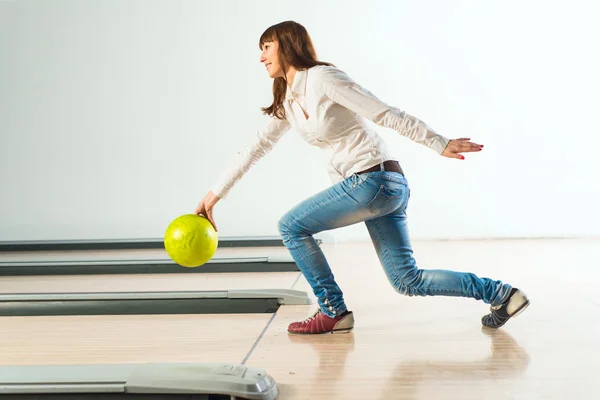 Agradável jovem mulher joga uma bola de boliche — Fotografia de Stock