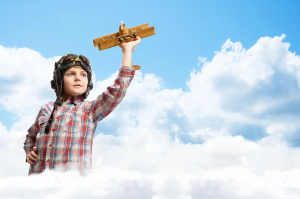 Garçon dans casque pilote jouer avec un jouet avion — Photo