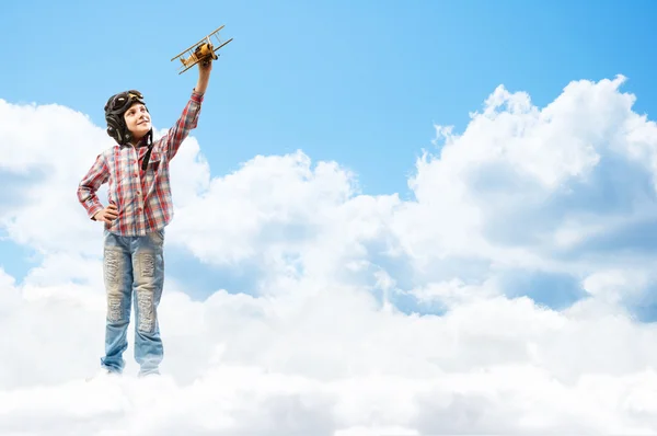 Menino no piloto de capacete brincando com um avião de brinquedo — Fotografia de Stock