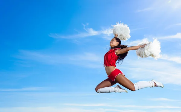 Jovem cheerleader em vermelho traje saltando — Fotografia de Stock