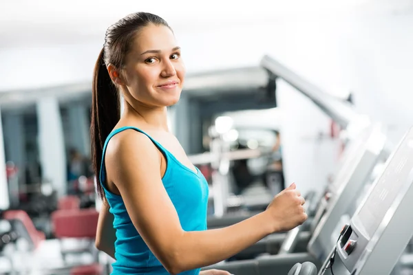 Attractive young woman runs on a treadmill — Stock Photo, Image