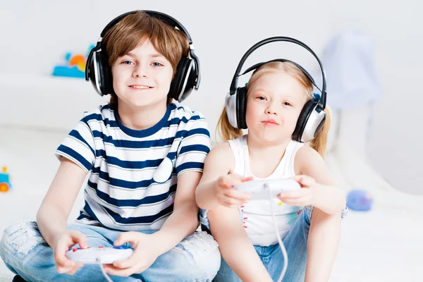 Lindo chico y chica jugando consola de juegos — Foto de Stock