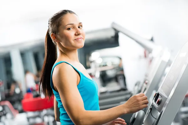 Attraente giovane donna corre su un tapis roulant — Foto Stock