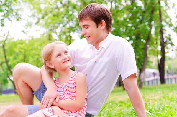 Father and daughter sitting together on the grass — Stock Photo, Image