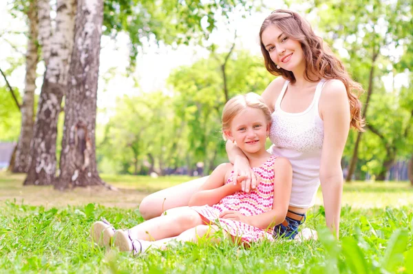 Anne ve kızı birlikte çimlerde oturan — Stok fotoğraf