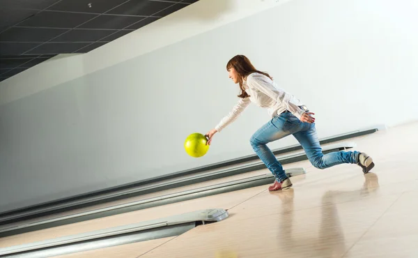 Agradável jovem mulher joga uma bola de boliche — Fotografia de Stock