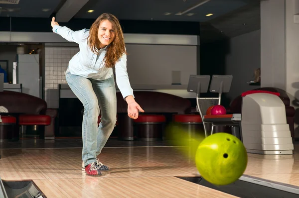 Pleasant young woman throws a bowling ball — Stock Photo, Image