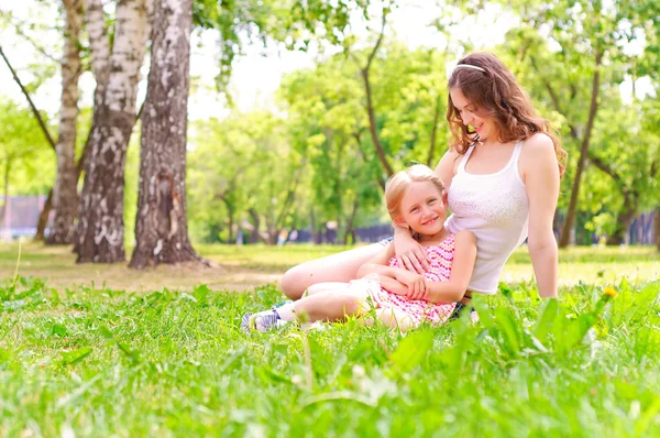 Matka i córka razem siedząc na trawie — Zdjęcie stockowe