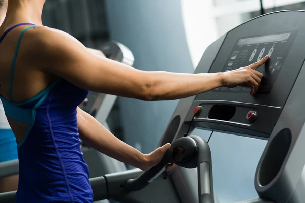 Woman adjusts the treadmill — Stock Photo, Image