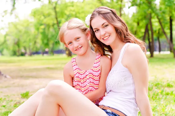 Mother and daughter sitting together on the grass — Stock Photo, Image