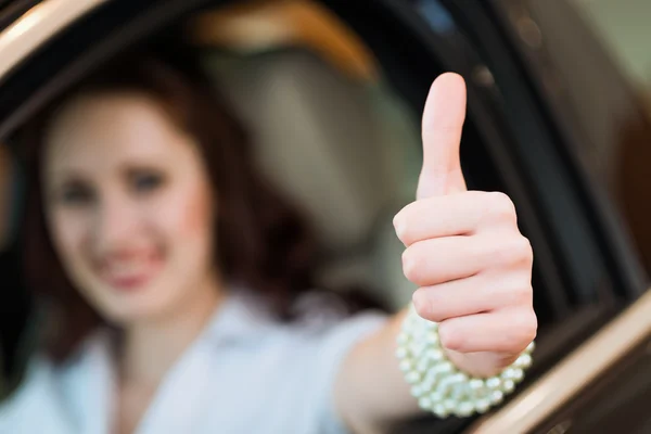 Giovane donna in macchina e mostrando un pollice in su — Foto Stock