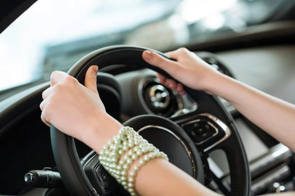 Τα χέρια της γυναίκας εκμετάλλευση προς το τιμόνι ενός νέου αυτοκινήτου — Φωτογραφία Αρχείου