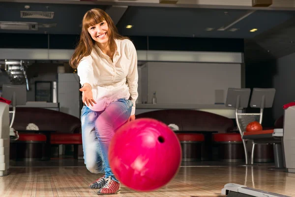 Agradável jovem mulher joga uma bola de boliche — Fotografia de Stock