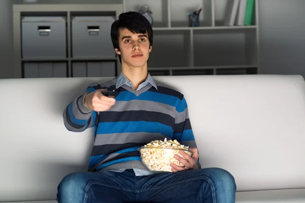 Ung man tittar på TV med popcorn — Stockfoto