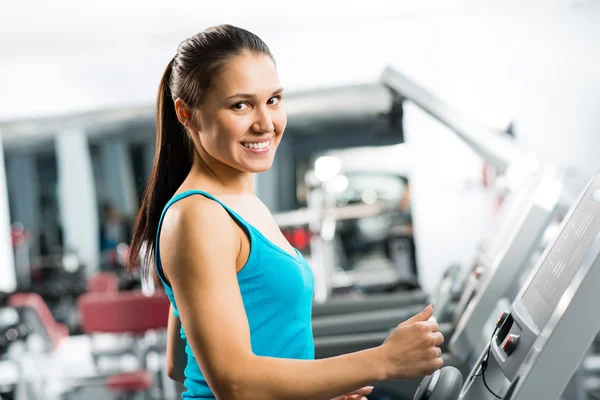 Attractive young woman runs on a treadmill — Stock Photo, Image