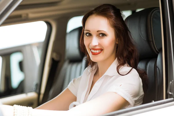 Ung kvinna i den nya bilen i utställningslokalen — Stockfoto