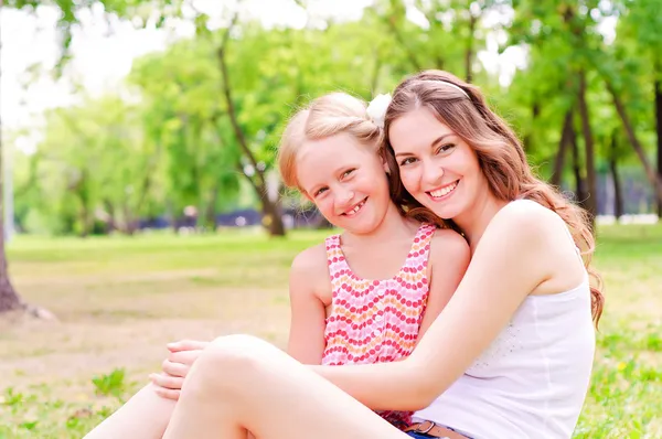 Mor och dotter sitter tillsammans på gräset — Stockfoto