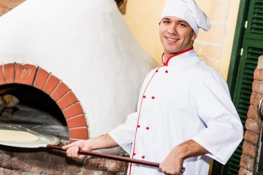 Şef, pizza fırını hamur koyar.,