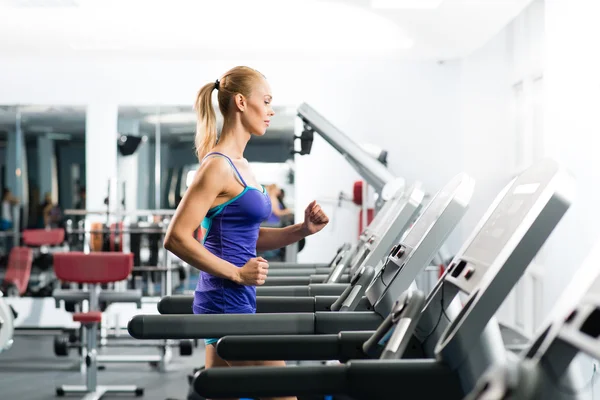 Attractive young woman runs on a treadmill — Stock Photo, Image