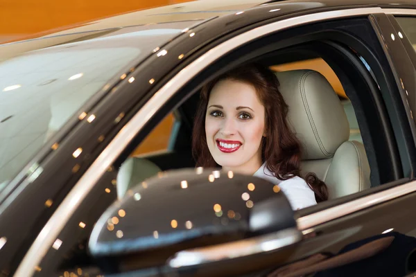 Jovem mulher no carro novo no showroom — Fotografia de Stock