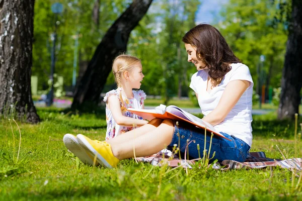 Menina e uma jovem mulher lendo um livro juntos — Fotografia de Stock