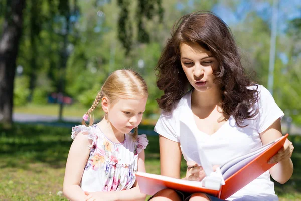 Girl and a young woman reading a book together — Stock Photo, Image