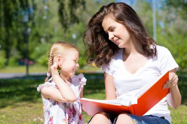 Menina e uma jovem mulher lendo um livro juntos — Fotografia de Stock