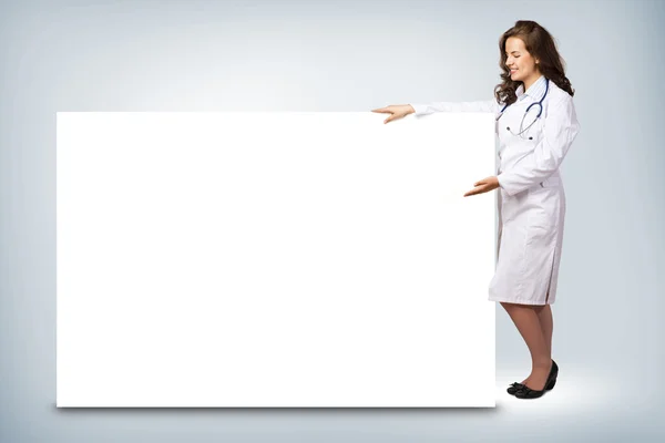 Jeune femme médecin debout près d'une bannière vierge — Photo