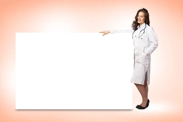 Mujer joven médico de pie cerca de una pancarta en blanco — Foto de Stock