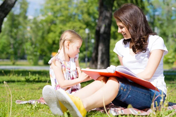 Chica y una mujer joven leyendo un libro juntos —  Fotos de Stock