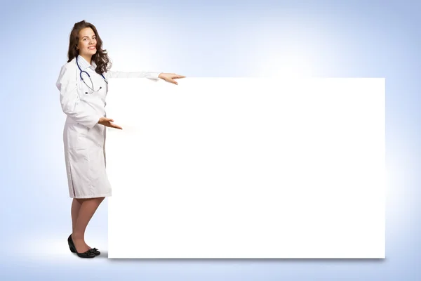Młoda kobieta lekarz stojący w pobliżu pusty transparent — Zdjęcie stockowe