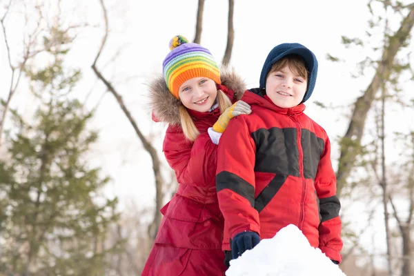 Pojke och flicka som leker med snö i vinter park — Stockfoto