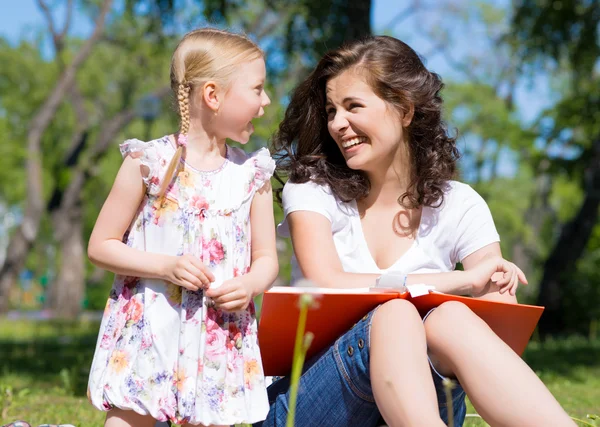 Girl and a young woman reading a book together — Stock Photo, Image