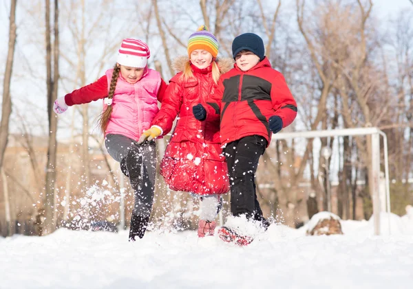 Ragazzo e ragazze che giocano con la neve nel parco invernale — Foto Stock