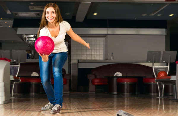 Agradável jovem mulher joga uma bola de boliche — Fotografia de Stock