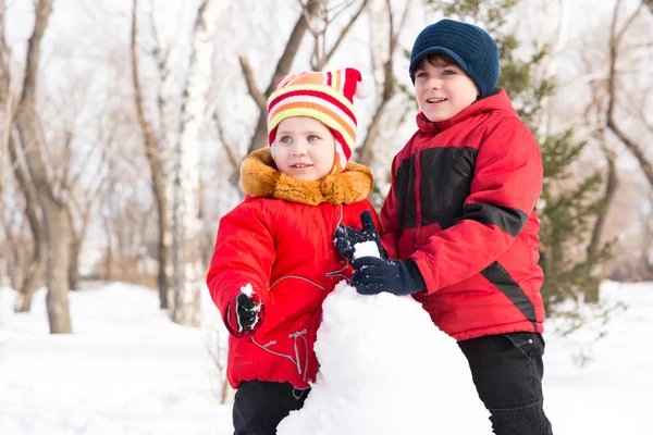 Menino e menina brincando com neve no parque de inverno — Fotografia de Stock