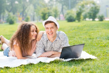 Çift birlikte parkta laptop ile yalan