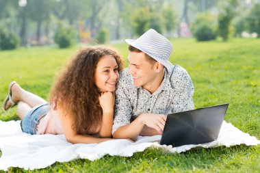 Çift birlikte parkta laptop ile yalan