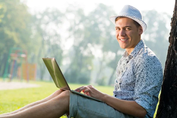 Young man working in the park with a laptop — Stock Photo, Image