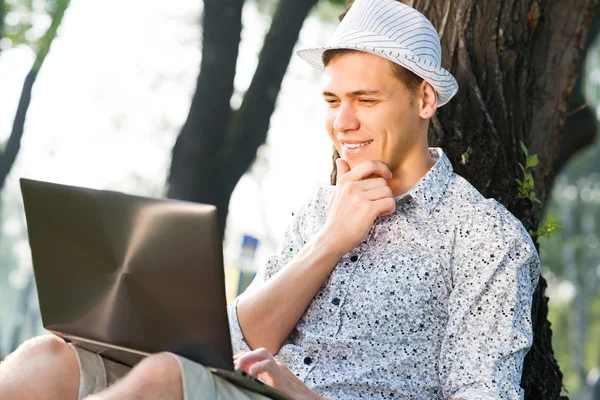 Młody człowiek pracujący w parku z laptopem — Zdjęcie stockowe