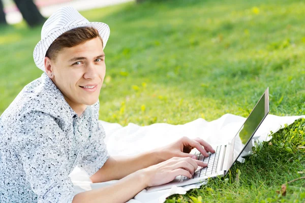 Young man working in the park with a laptop — Stock Photo, Image