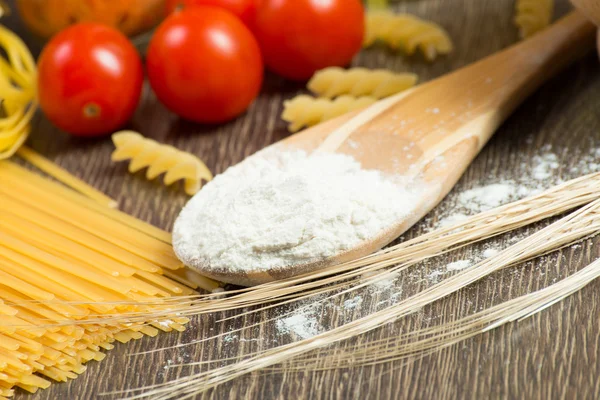 Pasta, tomatoes and flour on the spoon — Stock Photo, Image