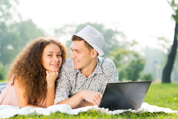 Para, leżąc razem w parku z laptopa — Zdjęcie stockowe
