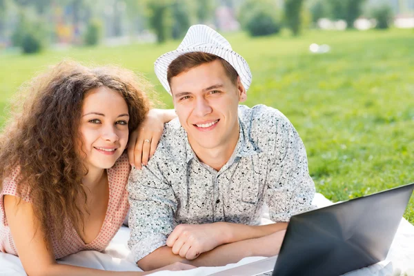 Paar liegt mit Laptop zusammen im Park — Stockfoto