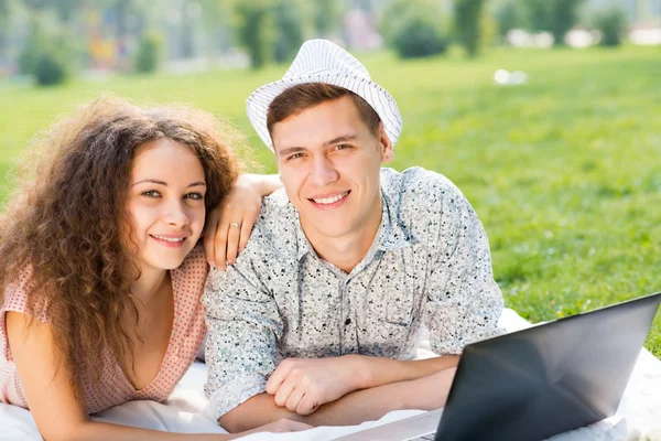 Pareja acostada en un parque con portátil —  Fotos de Stock