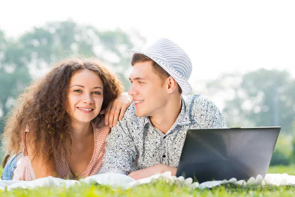 Pareja acostada en un parque con portátil — Foto de Stock